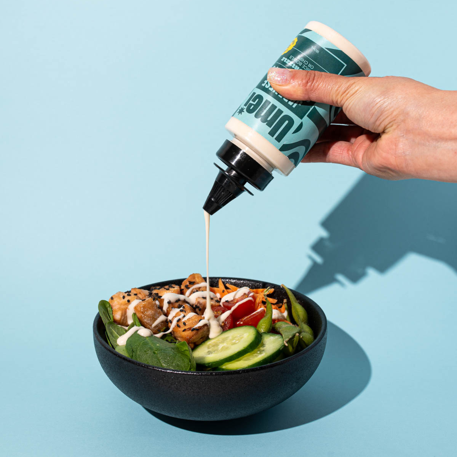 Umei Japanese style mayo drizzling on salmon rice bowl with blue background